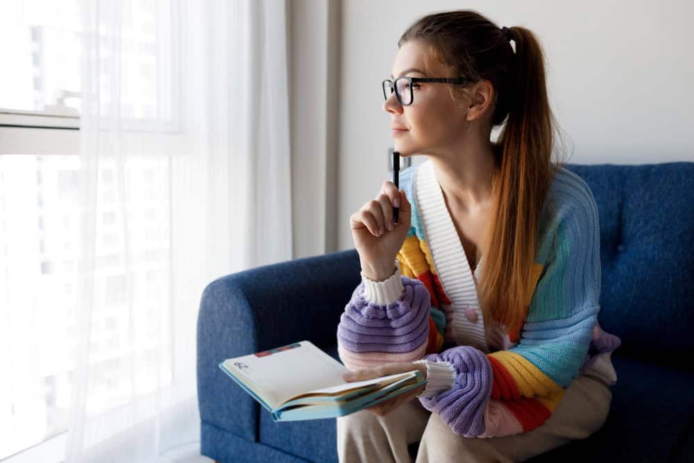 Woman taking notes at home during online ADHD therapy in North Carolina with 1Eleven Behavioral Health.