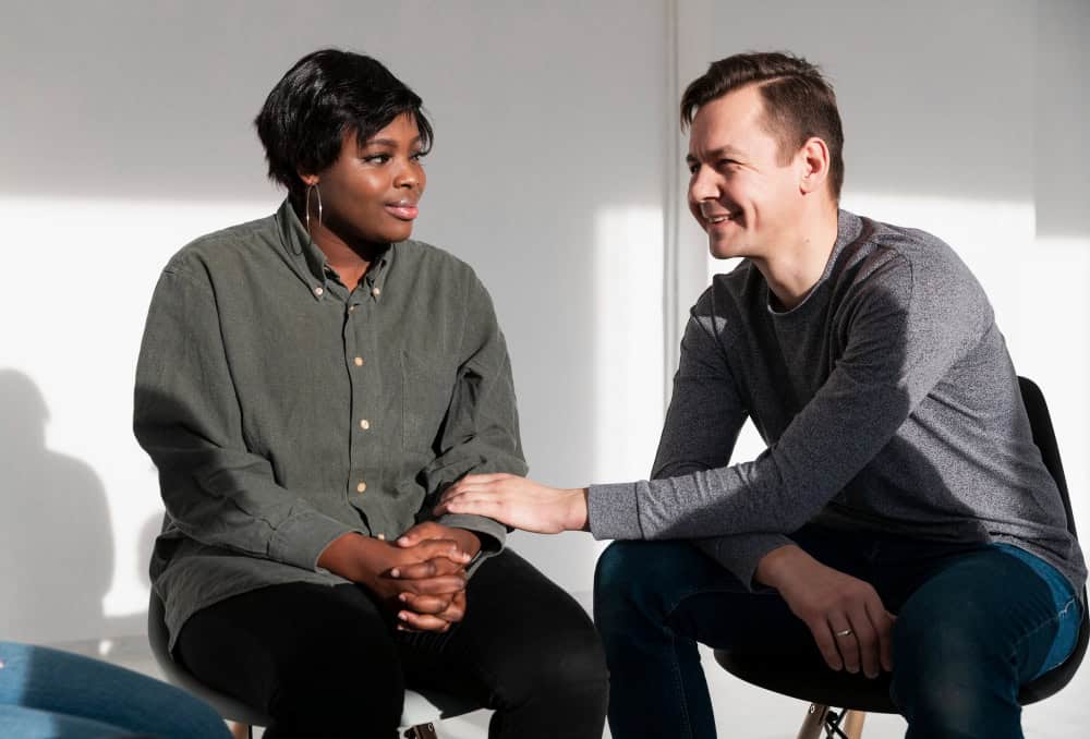 Man encouraging a woman during a therapy session while demonstrating the effectiveness of virtual IOP at 1Eleven Behavioral Health.