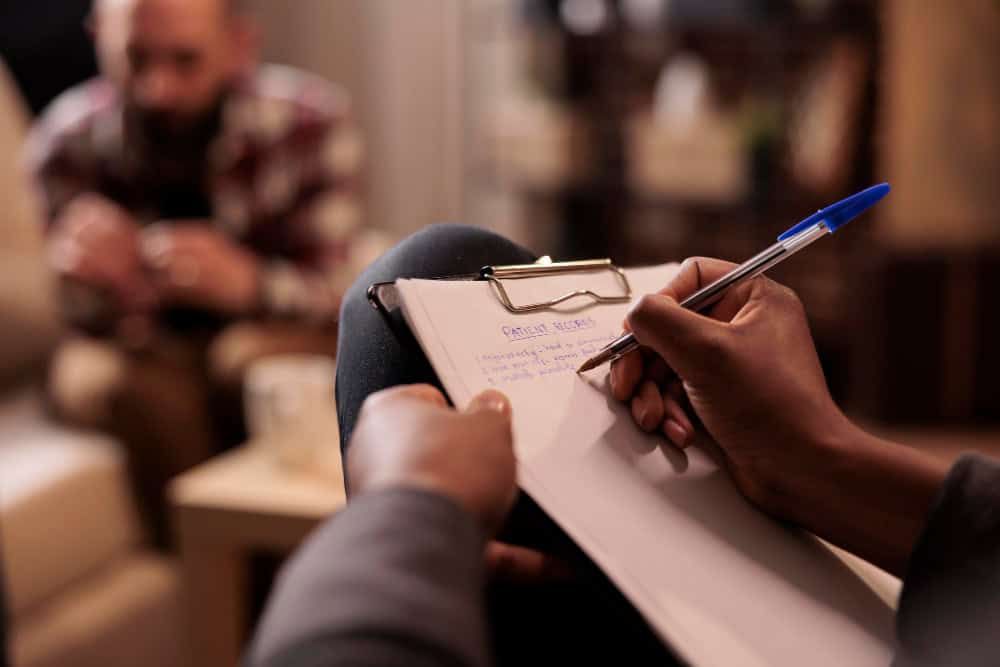 Male psychologist taking notes during a counseling session as part of opioid rehab in Greensboro, NC at 1Eleven Behavioral Health.